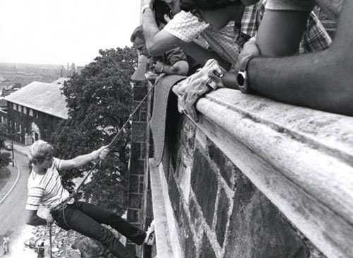 Students watch as an ROTC cadet rappels down Grace Hall