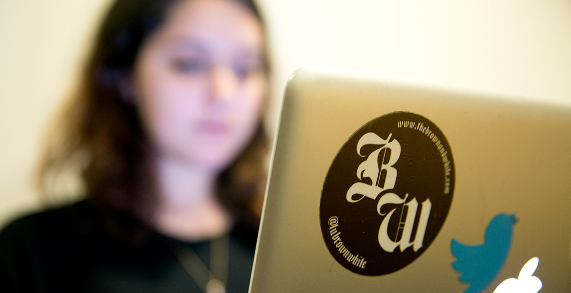 Brown and White newspaper student working at a computer