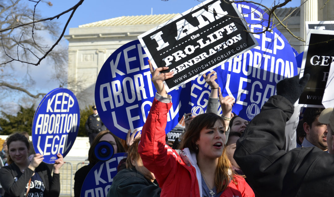 Pro- and anti-abortion protesters hold signs