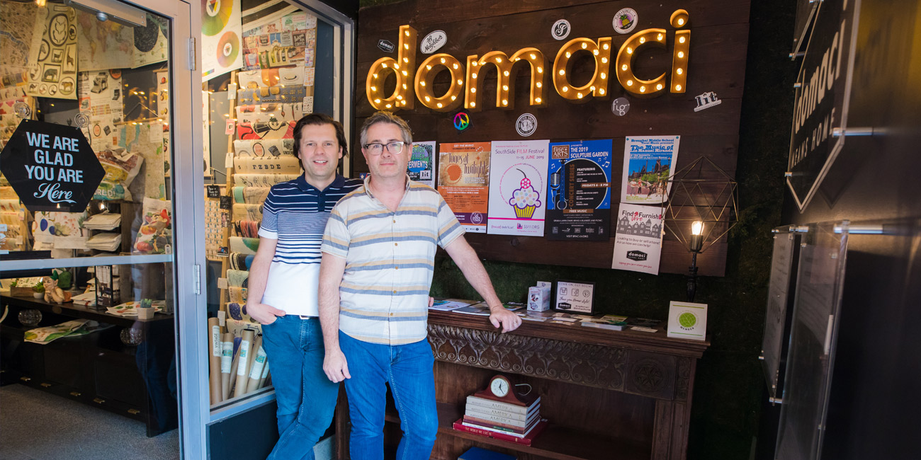 Two people standing in front of Domaci sign