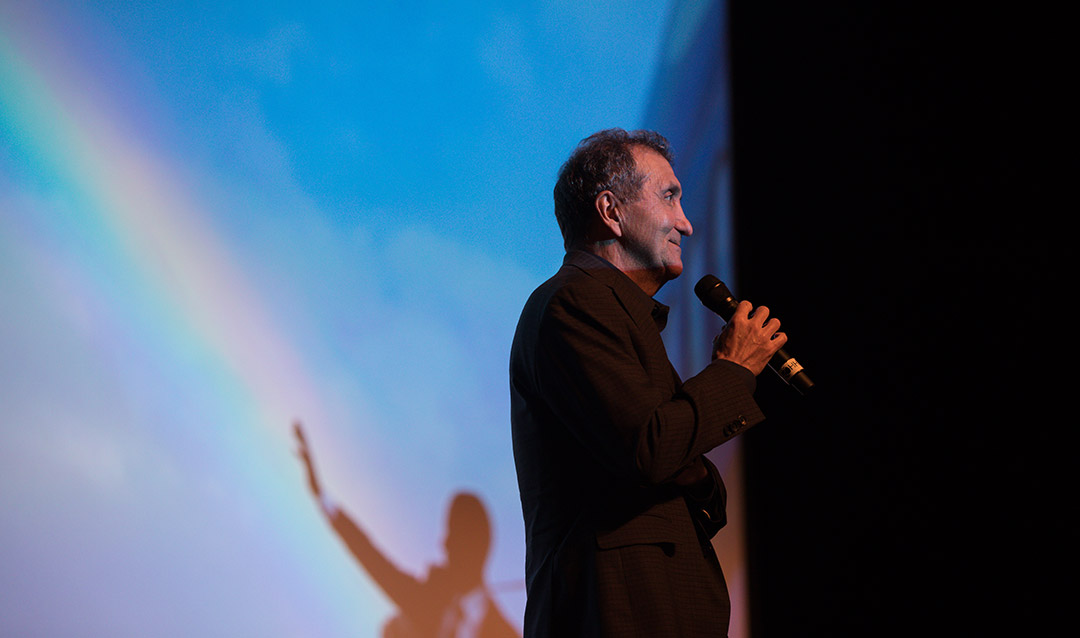 Pete Souza speaking in front of a photo he took of President Barack Obama and a rainbow