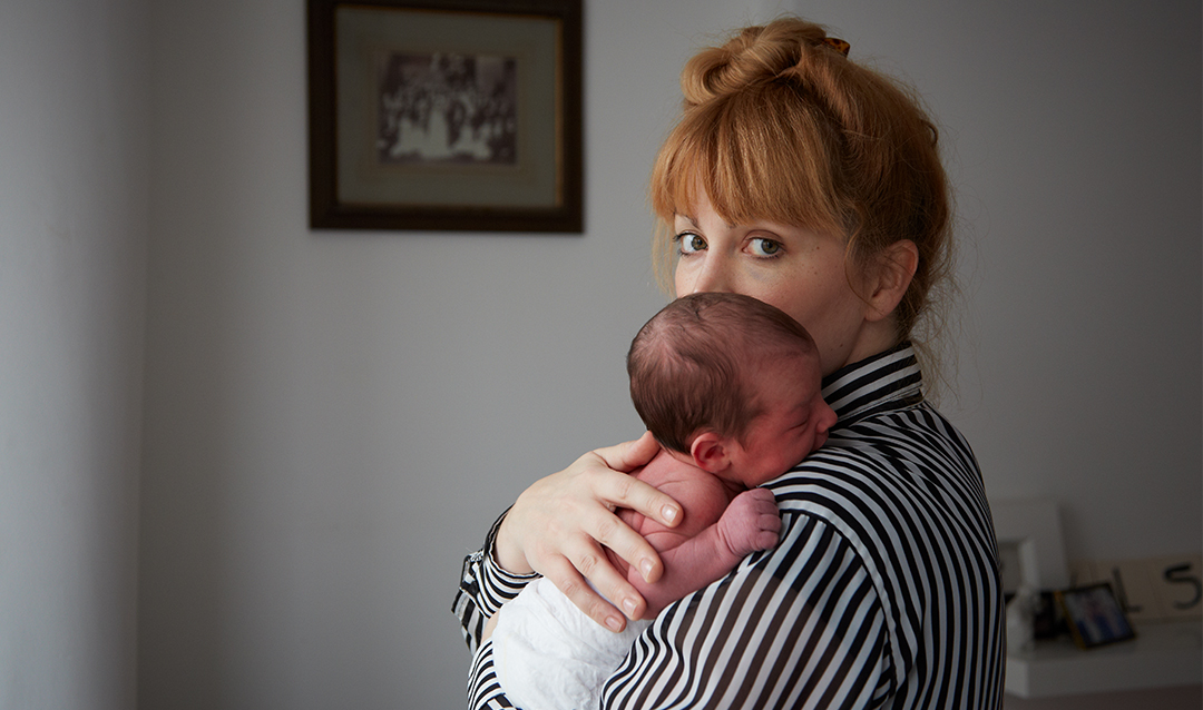 Photo of woman staring at camera, holding infant