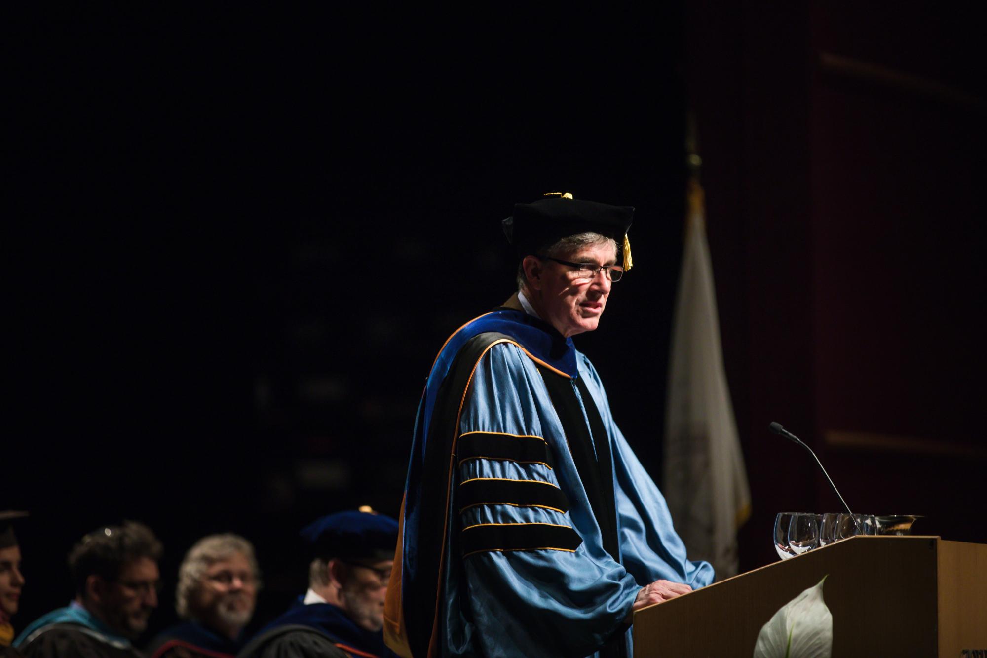 Lehigh Provost Pat Farrell speaks at the Honors Convocation while wearing regalia. 