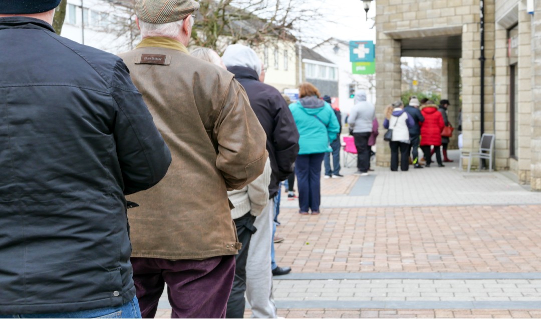 People standing in line outside a pharmacy