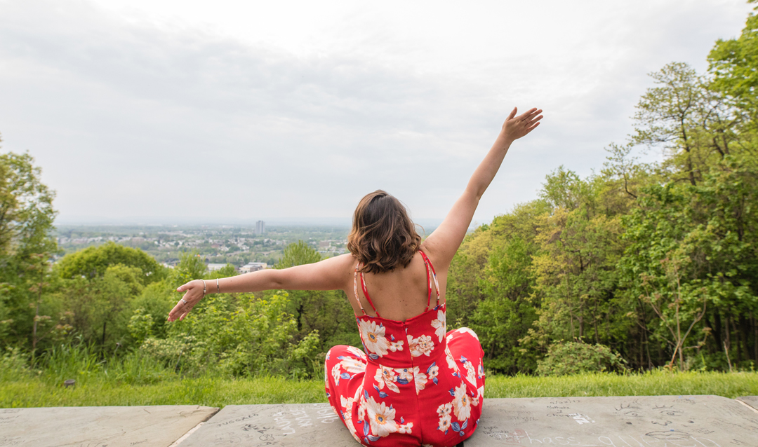 view from behind woman in red sundress sitting atop Lehigh lookout overlooking Bethlehem, PA