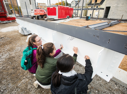 Students sign beam at College of Business.