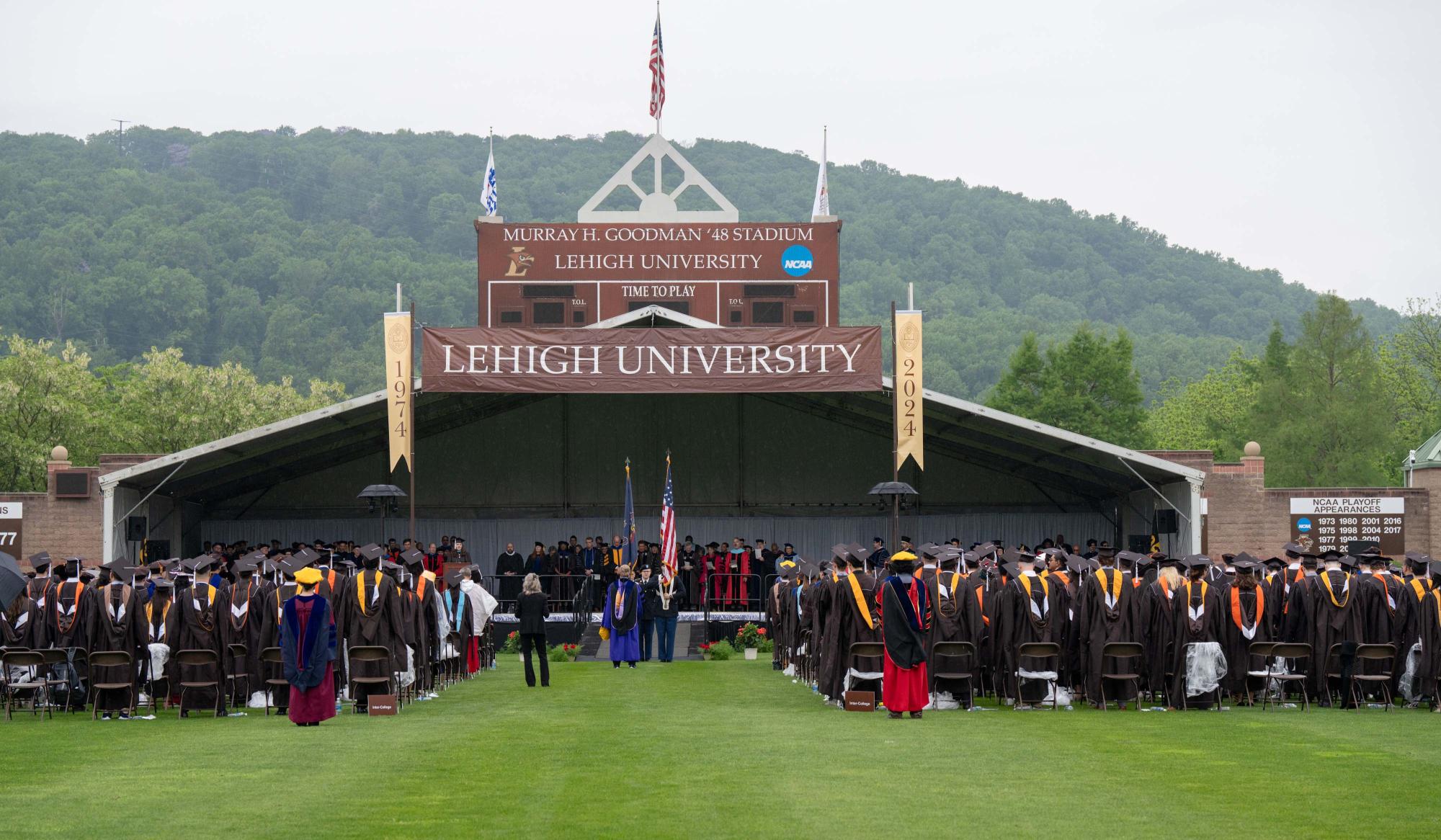 Graduates standing in front of stage at Goodman Stadium