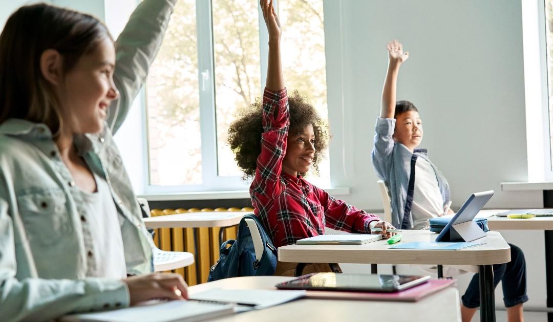 children raising hands in classroom