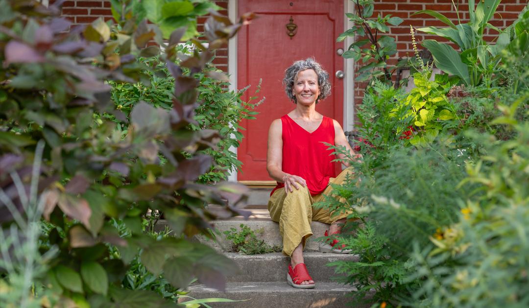 Deirdre Murphy, assistant teaching professor of art, sits near a garden.