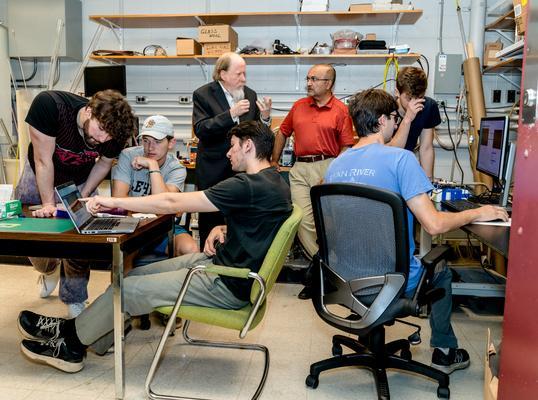 Students and professors collaborate in a busy lab setting.