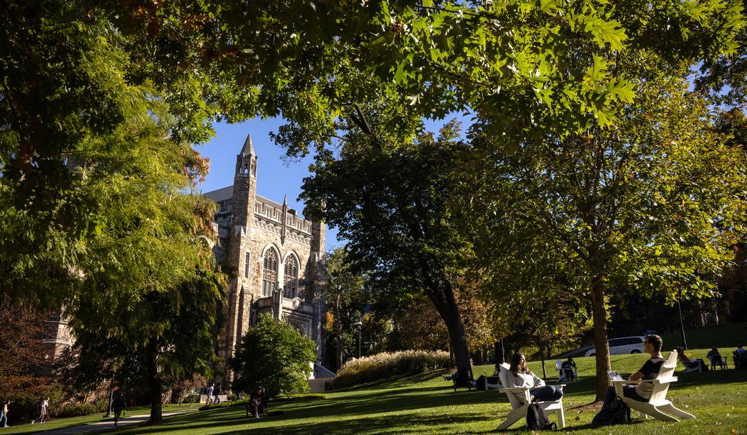 Students sitting on a lawn in front of a historic building