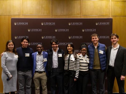 A group of students gathered for a photo in front of a Lehigh-branded backdrop.