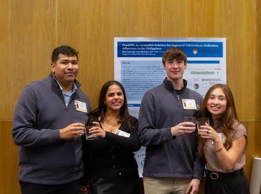 Four students clinking glasses in a posed photo