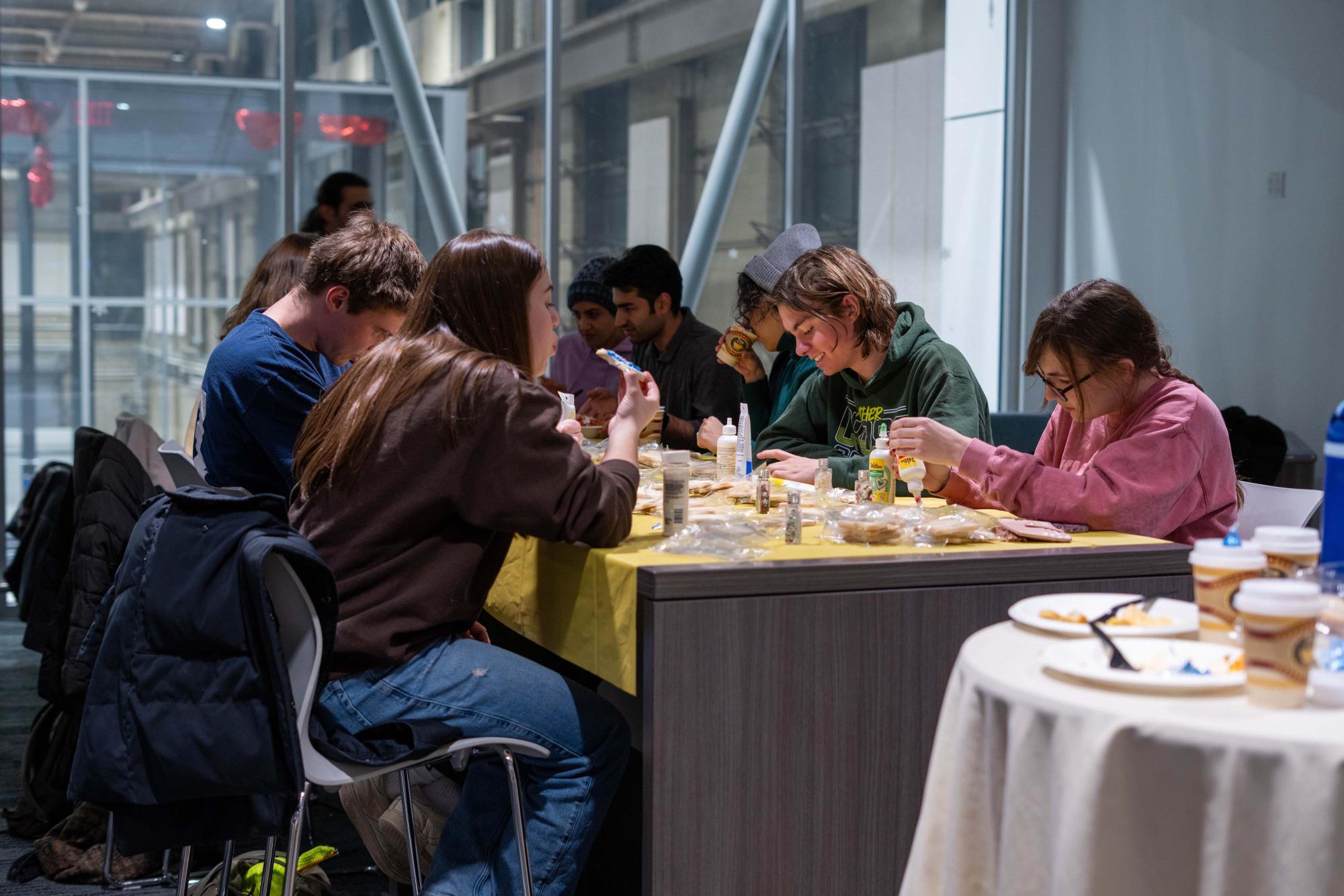 Group of people seated at a table, engaging in an activity, surrounded by a modern setting.