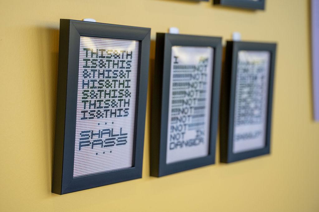 3 pieces of crosstitched work on display on a wall