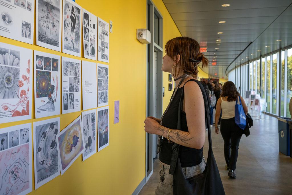 Woman looks at small collage of art on wall during art opening