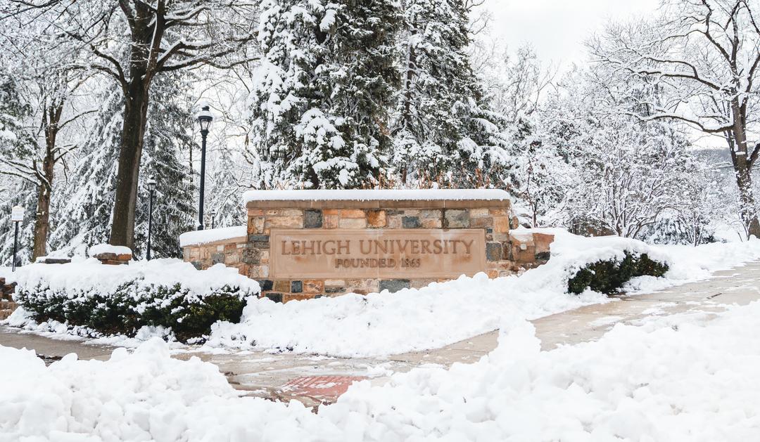 Lehigh University sign surrounded by snow in a winter setting.