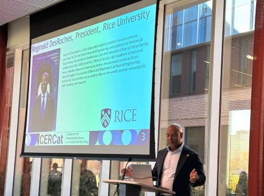 A man speaks at a podium with a presentation behind him.