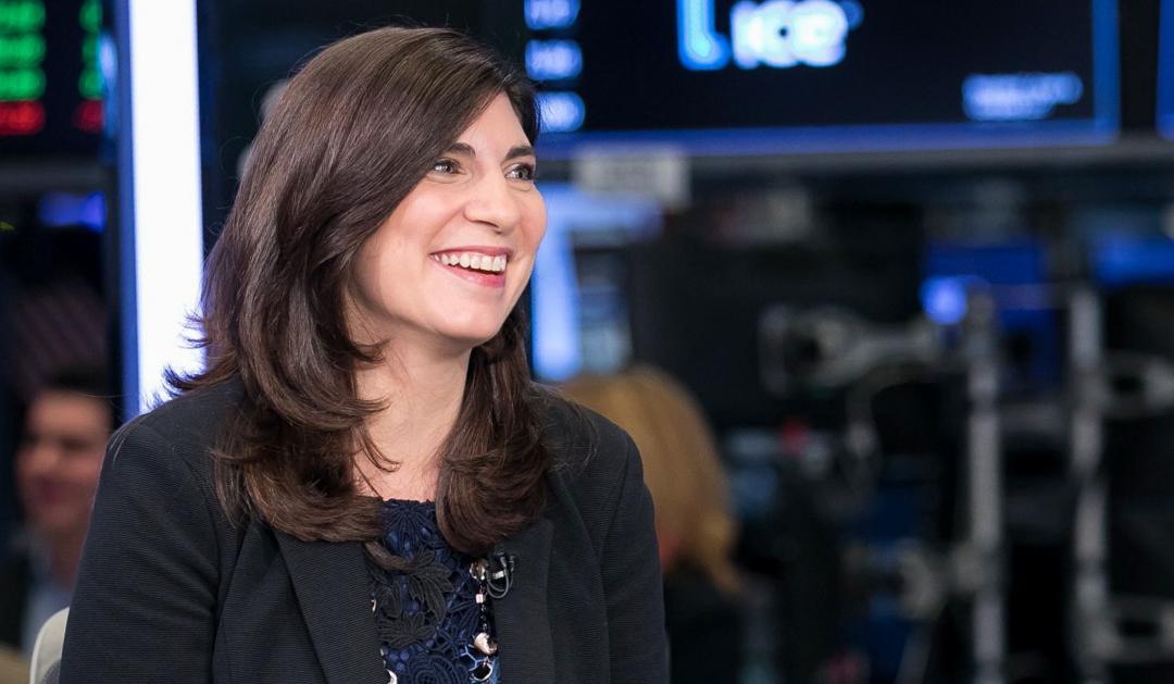 Stacey Cunningham is smiling in a blurred financial office setting.