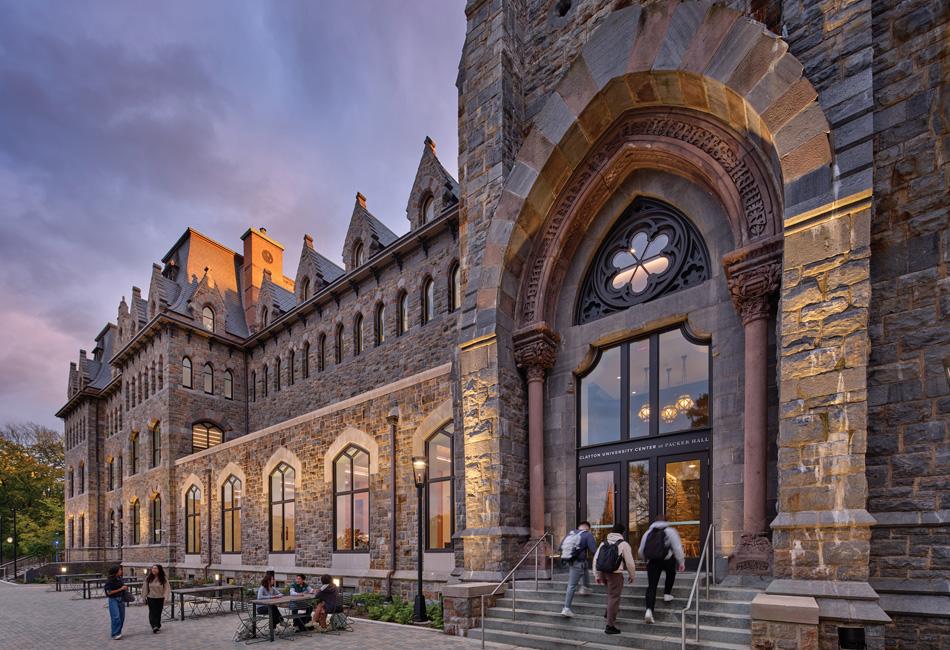 Historic stone building with arched entrance and students at sunset.
