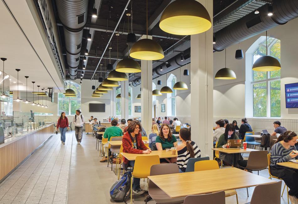 Students eating and walking in a busy, modern university cafeteria.