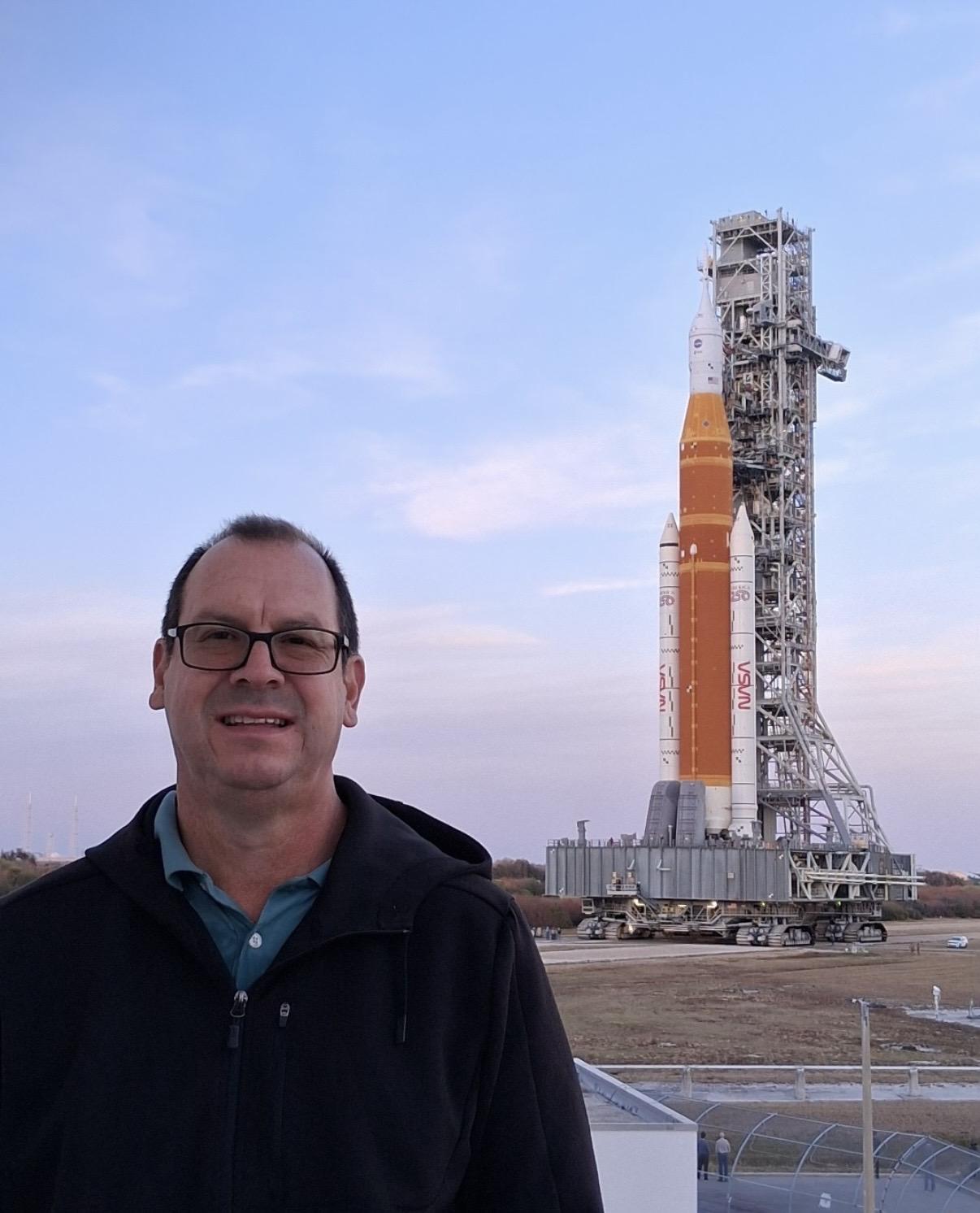 Photograph of Mark Riddle with the SLS rocket on its launchpad in the background.