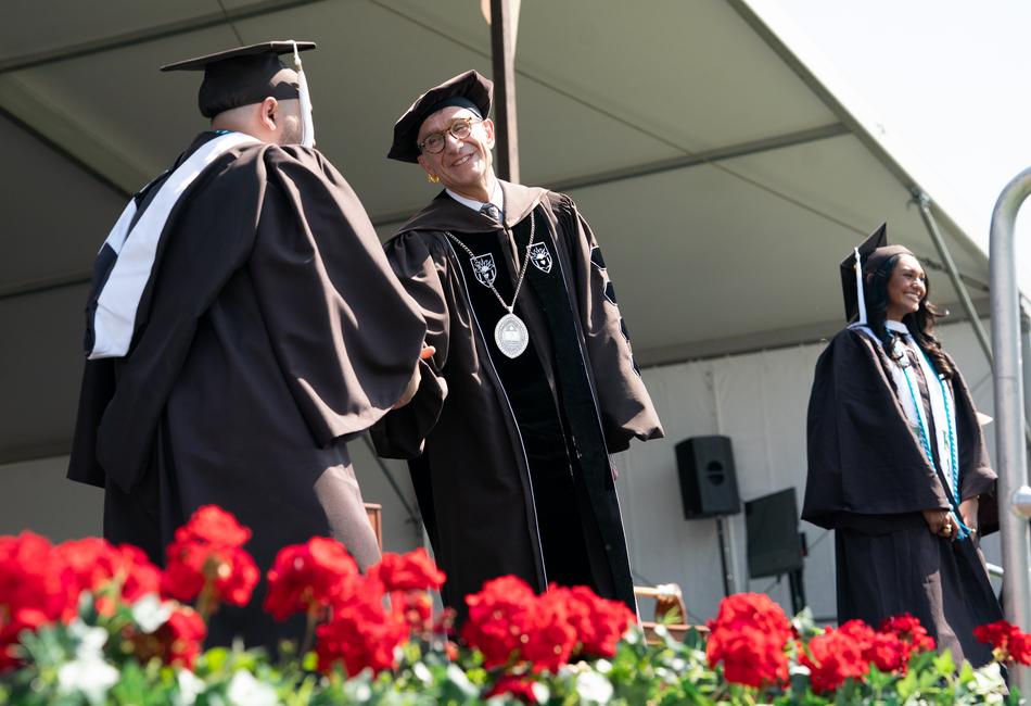 Photo of President Joseph J. Helble shaking stuents' hands at graduation.