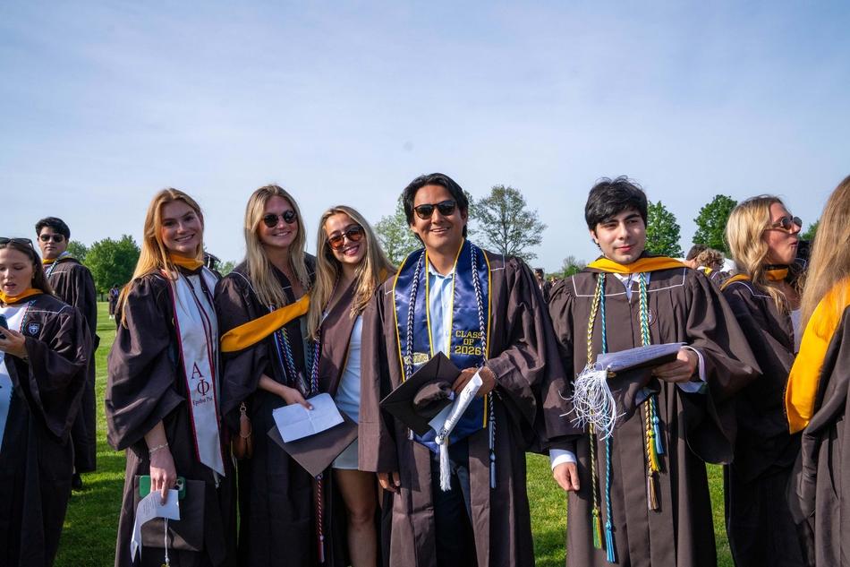 Students gather for a photo in their brown gowns. 