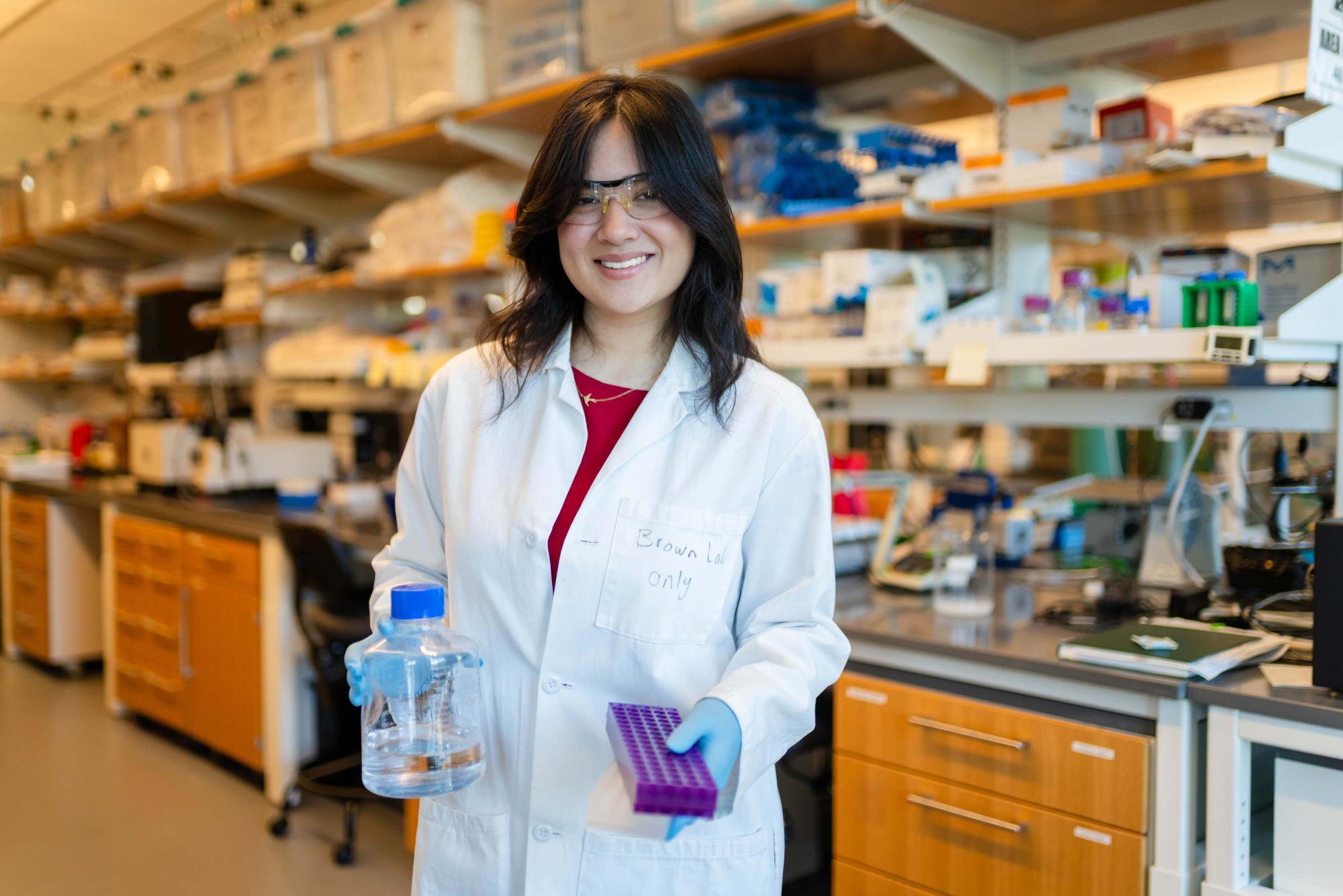 Photograph of Lillian Wu in a white lab coat holding laboratory equipment.