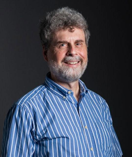 Photograph of a smiling man wearing a blue striped shirt.