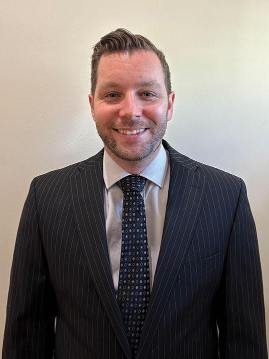 Headshot of a smiling man in a pinstripe suit and tie.