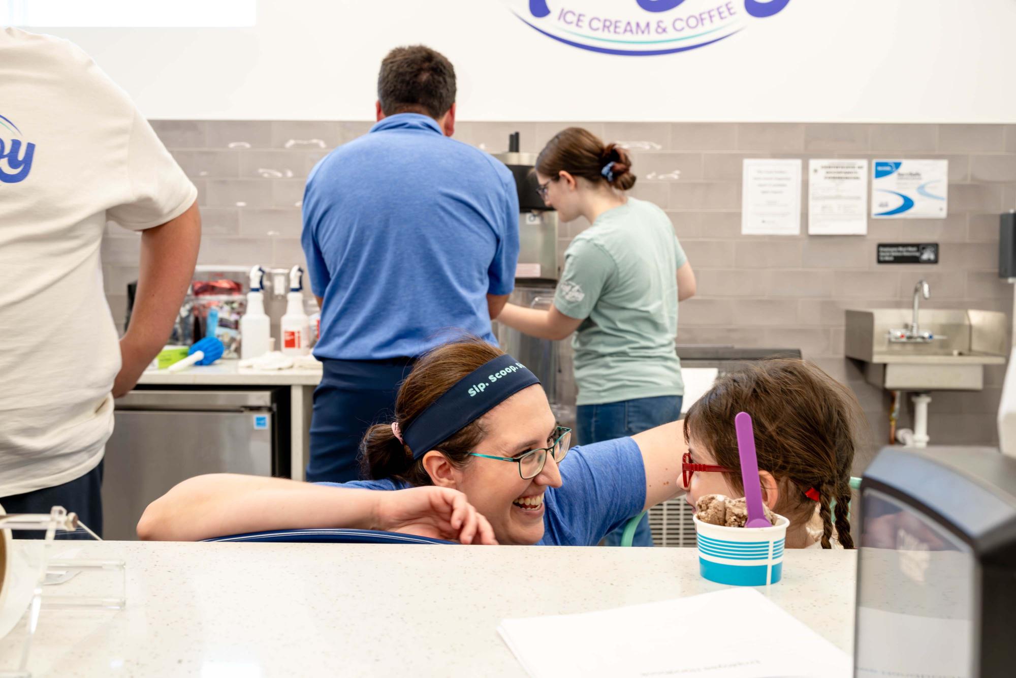 Photograph of a woman and young girl smiling at an ice cream shop counter.