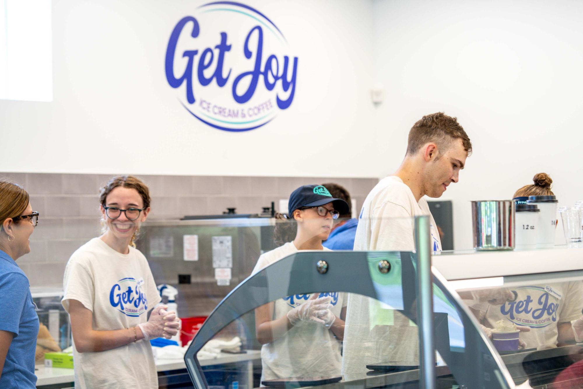 Photograph of smiling employees working behind the counter at Get Joy Ice Cream &amp; Coffee shop.