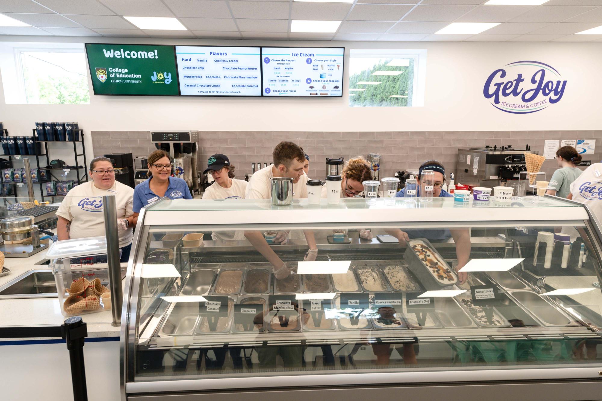 Photograph of smiling staff behind an ice cream display case at a Get Joy shop.