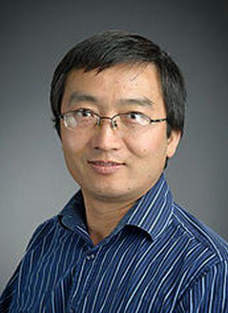 Headshot photograph of a man with glasses and a blue striped shirt.