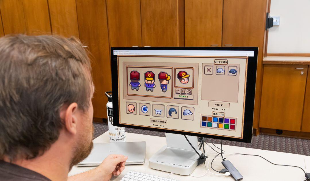 Photograph of a man looking at a character customization screen for a pixel art video game.