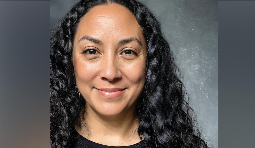 Photograph of a smiling woman with long curly black hair.