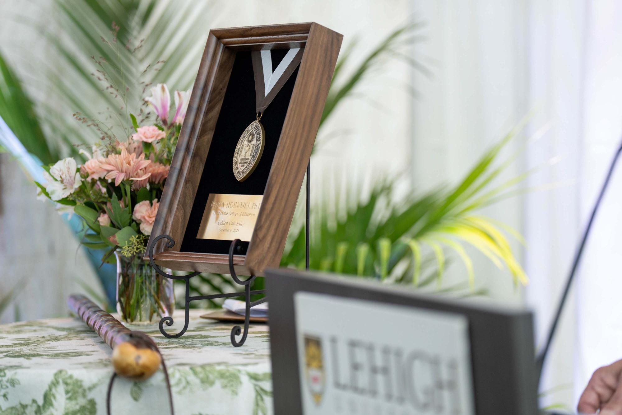 Photograph of a framed medal and flowers at a Lehigh University event.
