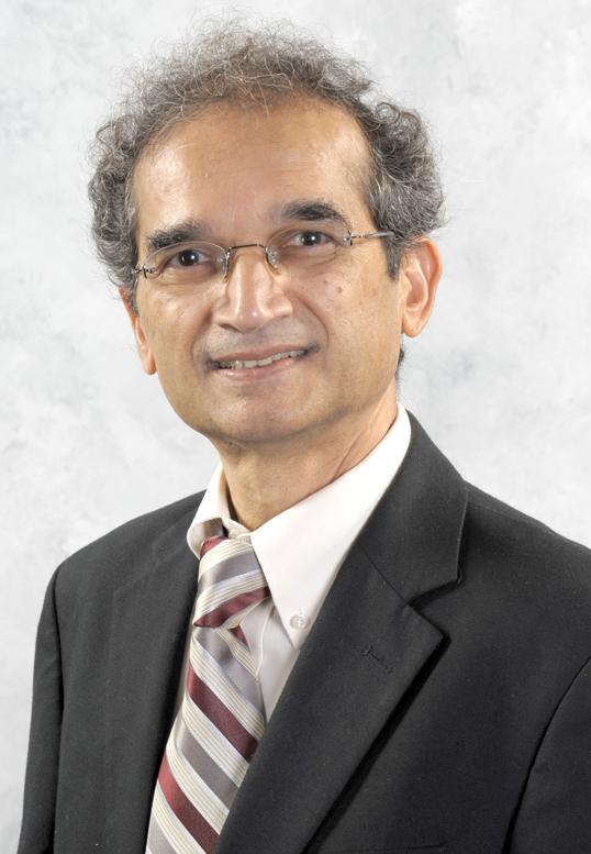 Photograph of a man wearing glasses, a suit, and a striped tie.