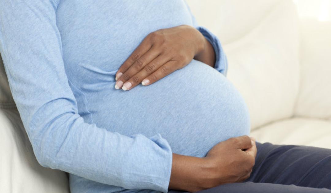 Unidentifiable pregnant woman with hands over belly