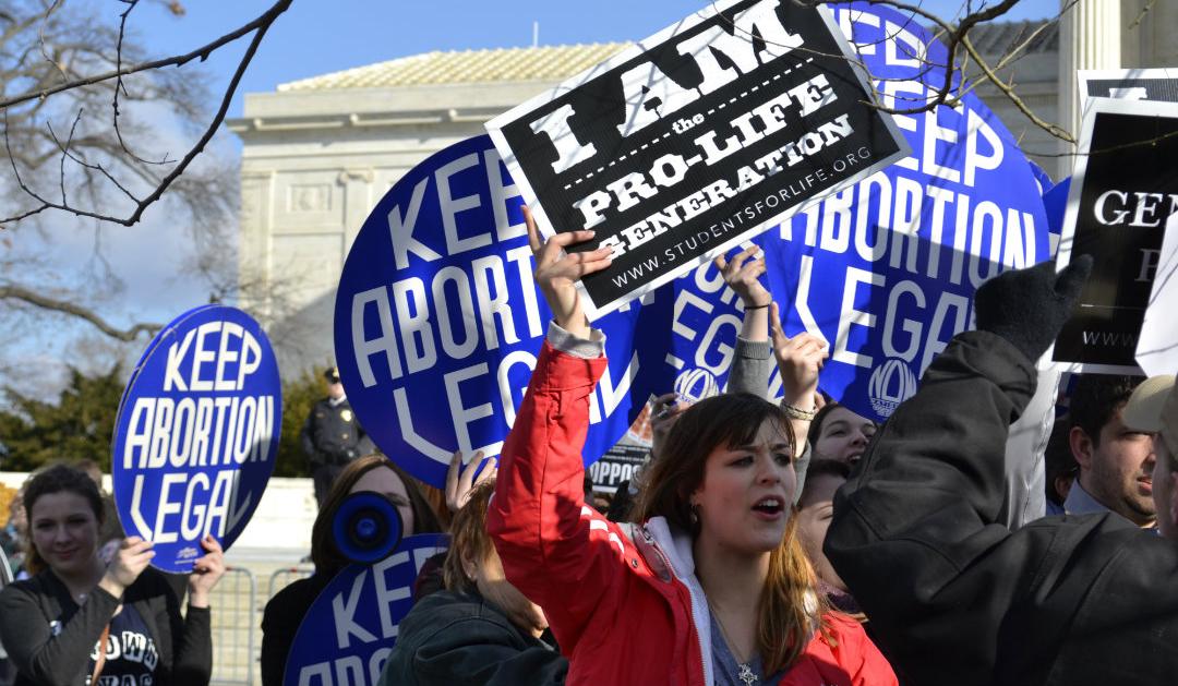 Pro- and anti-abortion protesters hold signs