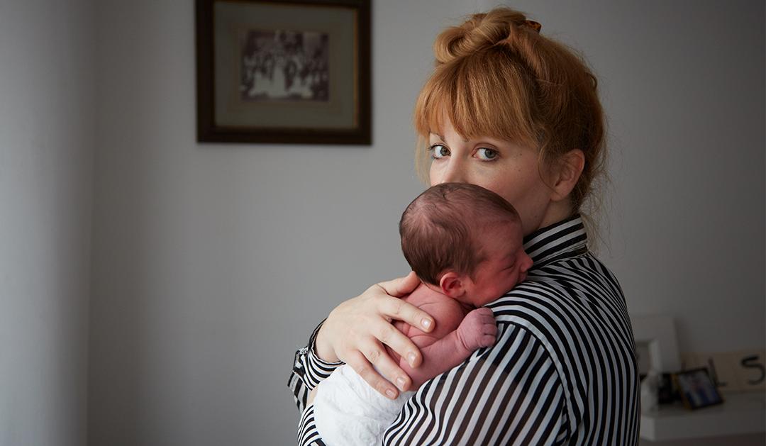 Photo of woman staring at camera, holding infant