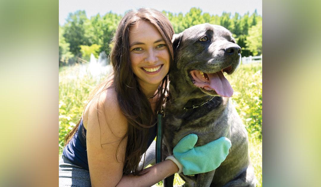 Student sitting next to a dog outdoors.