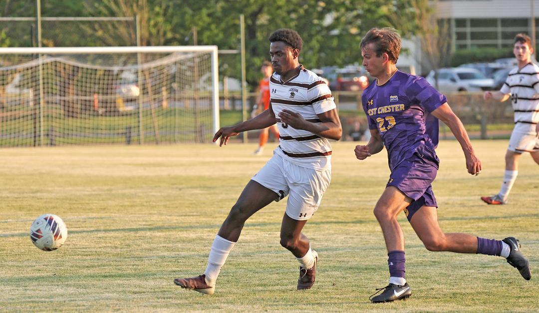 Soccer players in striped and purple jerseys compete for the ball on a field.