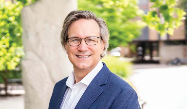 Portrait of man smiling and wearing glasses while looking at the camera.