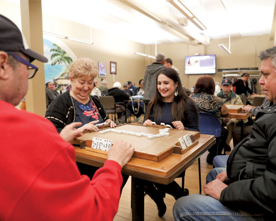 Students playing dominoes with seniors