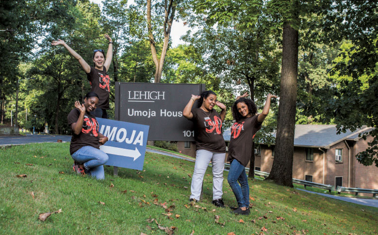 Students posing with the sign for the Umoja House