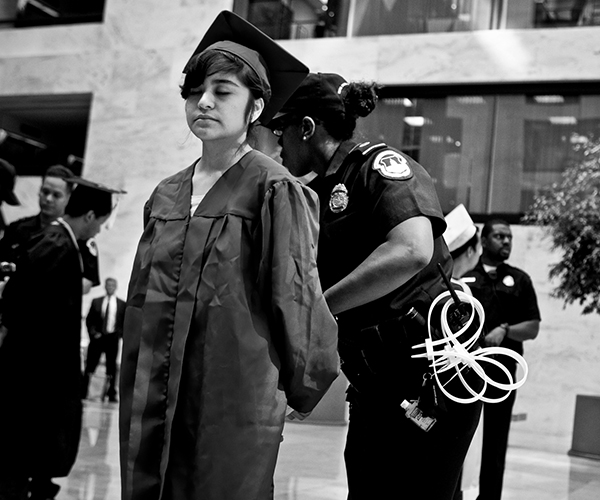 Person in graduation cap and gown being arrested