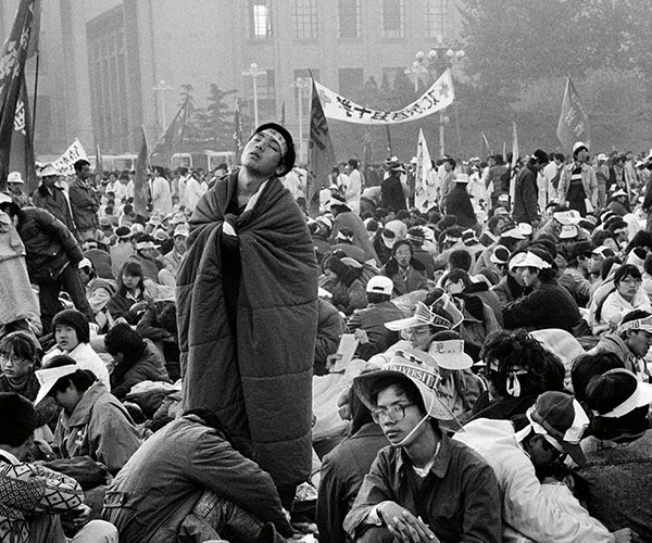 People walking on a bridge with people swimming in the water below