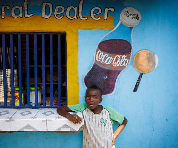 Boy leaning up against wall eating a sugary treat 